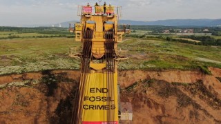 Na kolesovém rypadle je rozvěšeno několik transparentů. Aktivisty může vyhnat bouřka. Foto: Greenpeace